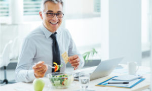 The man is eating a healthy meal at his working table.